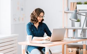 A smiling woman types on her laptop as she sits at her desk. This could represent the beneifts of ADHD productivity hacks that Focused Mind ADHD Counseling can teach. Learn more about your ADHD superpowers, and how an adult ADHD therapist in Columbus, OH can help you! 43017 | 43220  | 43235