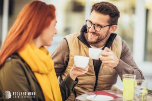 A smiling man and woman smile at one another while toasting their coffee cups. A therapist in Columbus Ohio can help you overcome feelings of rejection. Contact Focus Mind ADHD Counseling to learn more about online therapy in Columbus, Ohio and other services. 