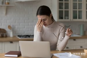 A woman touches her face while sitting in front of her laptop with an upset expression. Focused Mind ADHD Counseling can help you better understand ADHD symptoms Ohio. Learn more about anxiety symptoms Columbus, OH and emotional regulation therapy in Columbus, OH by contacting us today.