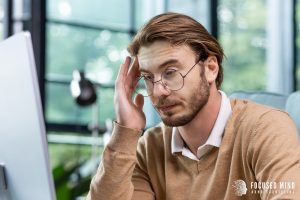 A man appears tired while looking at his computer screen. Learn how ADHD testing in Columbus, OH can offer support with realizing your ADHD superpowers. Learn more by searching for adhd testing columbus ohio today for support. 
