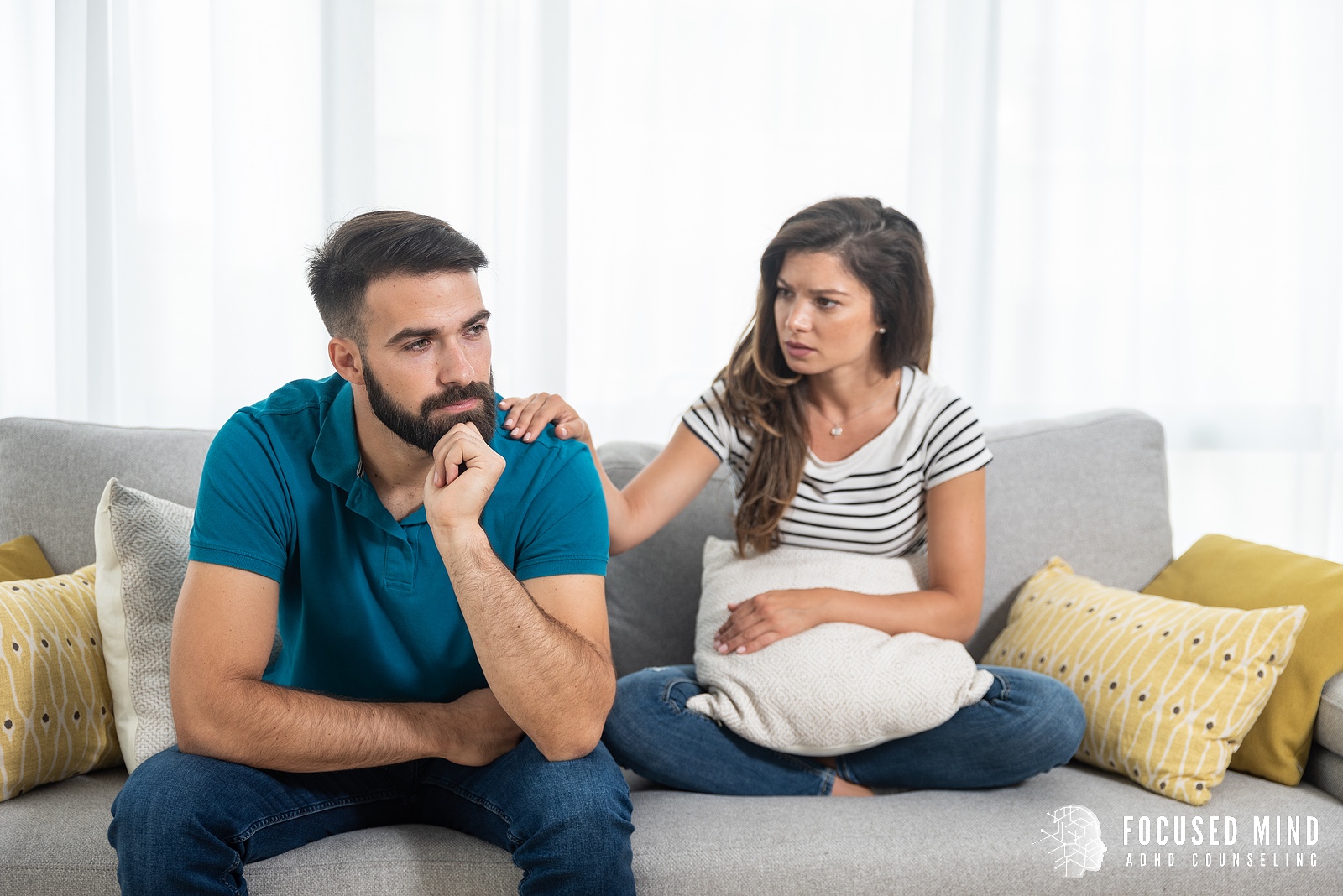 A woman touches the shoulder of her partner as both sit on a couch and talk. Learn how an adult ADHD therapist in Ohio can offer support with addressing people pleasing. Learn more about ADHD treatment for adults in Ohio and other services by searching for online ADHD treatment in Columbus, OH today.
