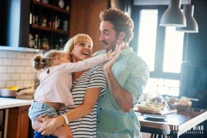 A family of three smiles at one another while high-fiving in the kitchen. Learn how online adhd treatment in Columbus, OH can help improve your relationships. Search for ADHD treatment for adults in Ohio today. 
