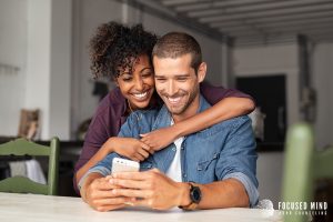 A happy couple smiling at a phone after progress in ADHD and emotional regulation work, thanks to emotional regulation therapy in Columbus, OH provided by an adult ADHD therapist in Ohio and support from an ADHD therapist for adults near me.