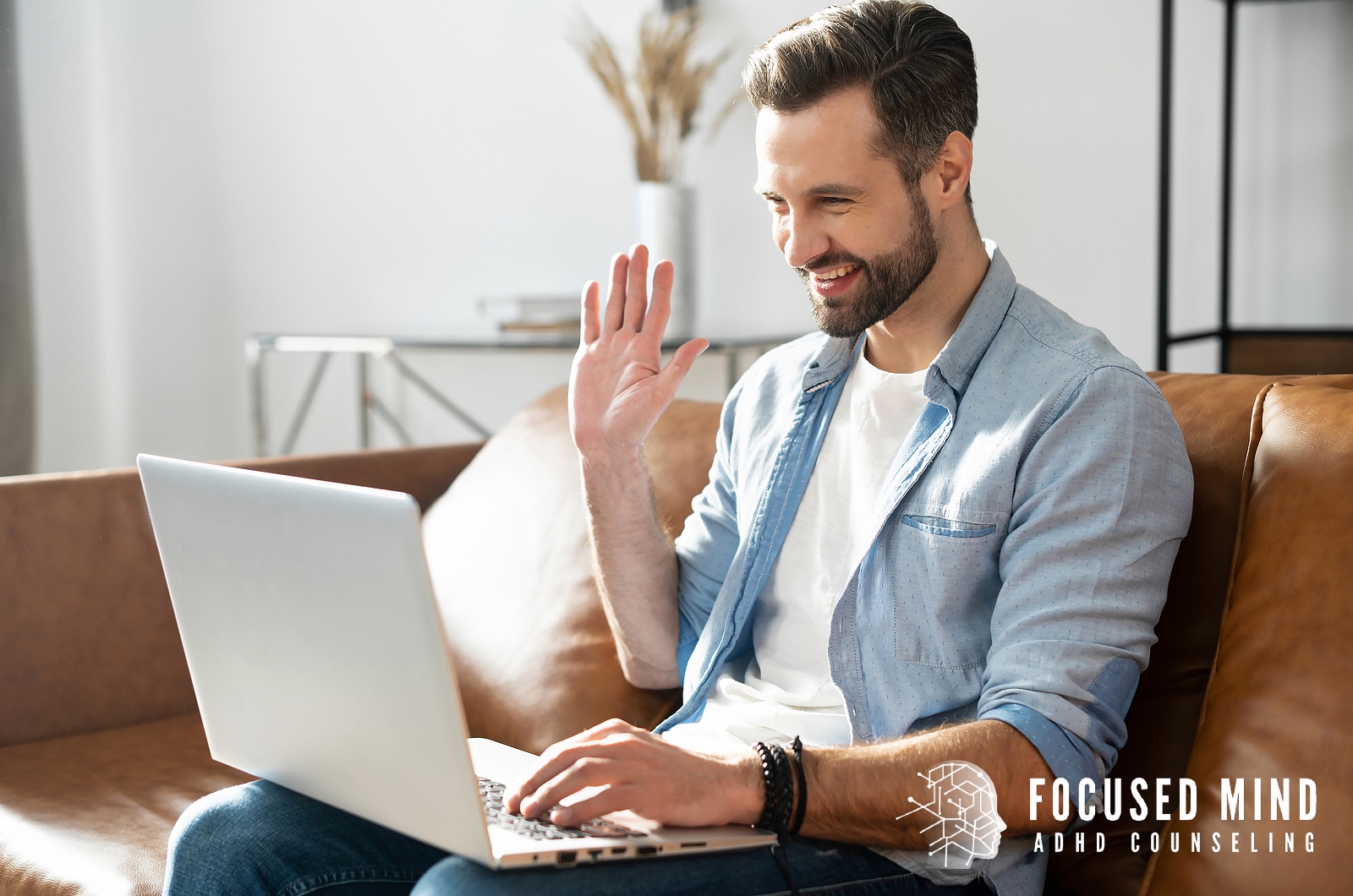 A man smiles and waves at his laptop during a video call from his living room. Are you unsure whether you need an ADHD diagnosis to understand your focus challenges? Online ADHD testing in Cleveland, OH, can give you clarity and support your next steps.