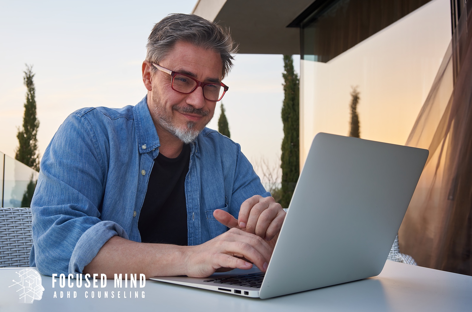 A man works on his laptop at an outdoor patio table as the sun sets behind him. Are you considering an ADHD assessment to understand patterns affecting work or daily tasks? An online ADHD therapist in Cleveland, OH, can guide you toward meaningful answers.