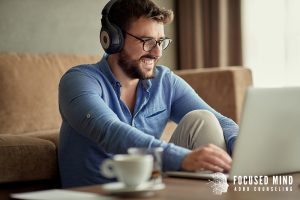 Man working on a laptop with headphones, using online adhd treatment in columbus, oh to stay on track while navigating adhd and anxiety in adults columbus, oh. Anxiety therapy in columbus, oh can also help reduce overwhelm and restlessness.